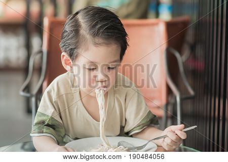 Cute Asian chid eating Spaghetti Carbonara in restaurantvintage fiter