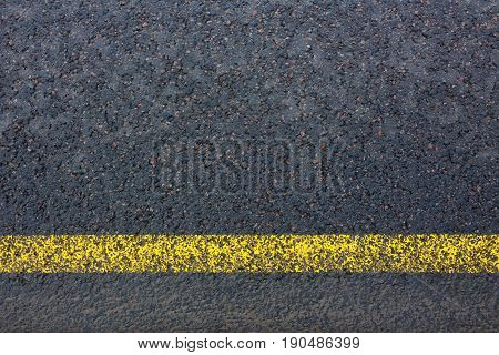 Road marking with yellow lines on dark asphalt close up