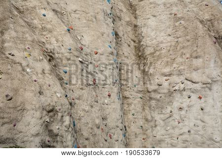 Structure of artificial rock-textured wall with coloured handholds and feetholds