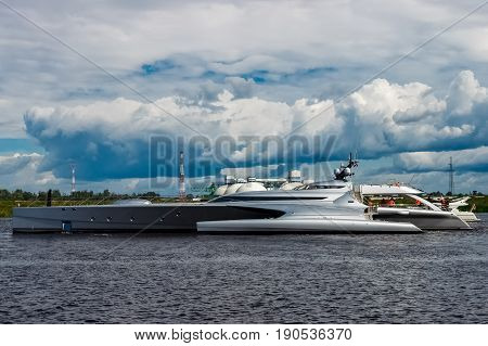 Large silver trimaran. Luxury yacht sailing by the river in Riga