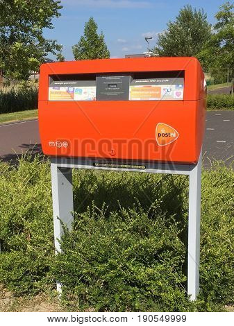 Almere Poort, Flevoland, The Netherlands - June 10, 2017: Orange PostNL mailbox standing on the side of a street in Almere . PostNL is the Dutch postal service.