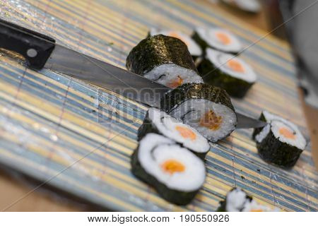 Maki Sushi With Smoked Salmon Being Cut