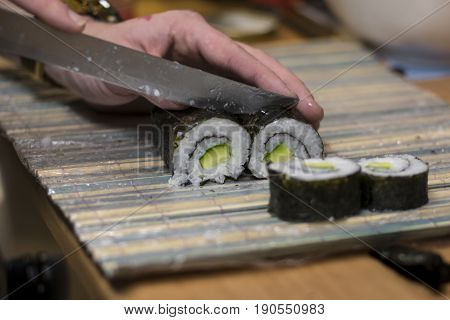 Fresh maki sushi with cucumber being cut