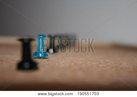 One blue pin among black ones in the cork-board