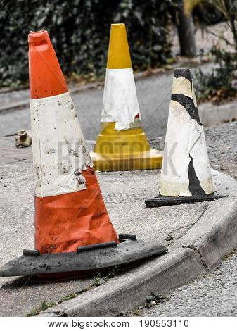 Three bouys of different colors on the pavement