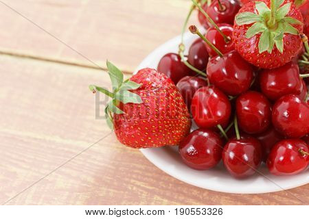 Fruit background cherry and strawberry on wooden table. View from above with copy space
