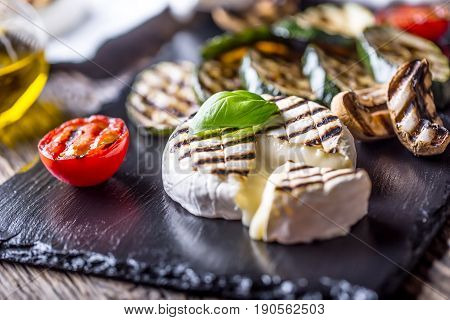 Camembert cheese. Grilled camembert cheese with zucchini tomatoes olive oil and basil leaves.