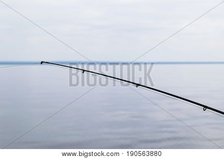 Boat fishing rod with the line over a beautiful cloudy seascape