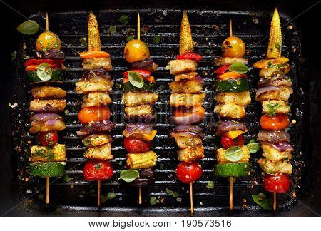 Vegetarian skewers with halloumi cheese and mixed vegetables on grill plate, top view