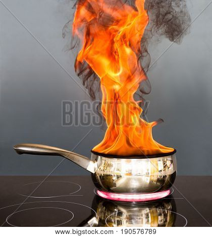 Saucepan on a hob with flames coming out of it like a chip pan fire