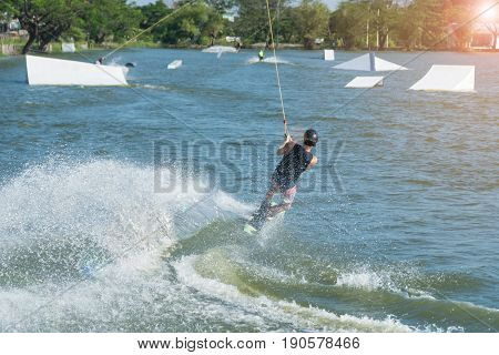 Handsome man wake boarding on a lake with cable in Thailand