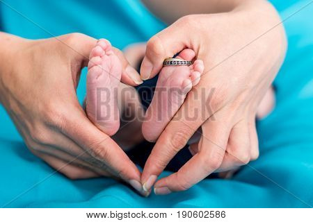 Mother's hands forming a hearth around baby feet. Fanily love.