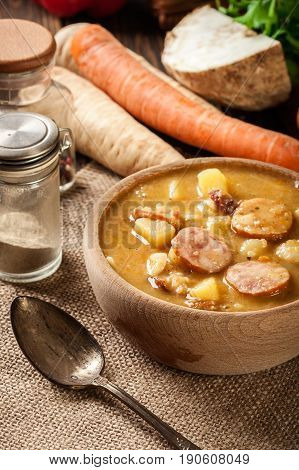 Wooden Bowl Of Split Pea Soup With Sausage And Potatoes