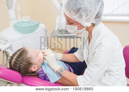 Young girl on a dental exam with female dentists.