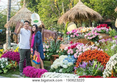 CHIANG MAI, THAILAND - FEBRUARY 6, 2016: Thai couple takes a selfie during Chiang Mai Flower Festival at Buak Hard Public Park in Chiang Mai. This year the world famous festival celebrated its 40th anniversary.
