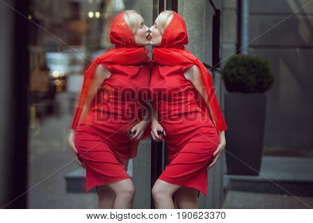 Woman kisses her reflection in the shop window she loves herself much.