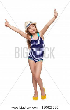 Full length child girl in swimsuit and summer hat giving double thumb up, over white background