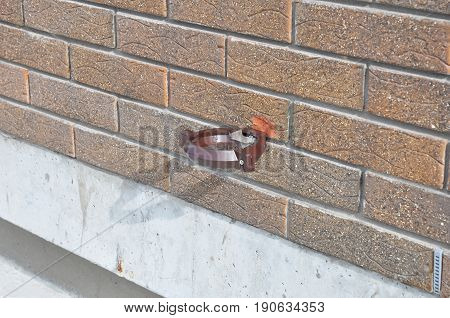 Plastic rain gutter holder for rain gutter downspout pipe. Installing rain gutter holder. Guttering.