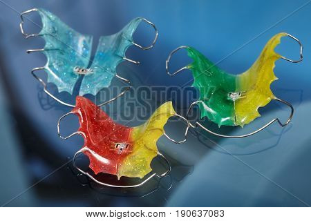 Colorful dental braces or retainers for teeth on blue glass background closeup