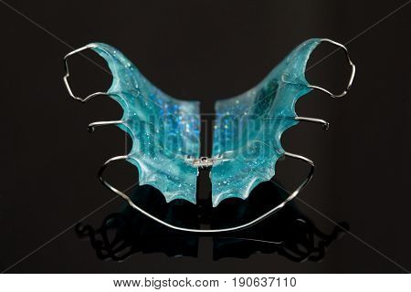 Colorful dental braces or retainers for teeth on black glass background closeup
