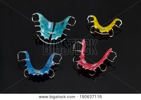 Colorful dental braces or retainers for teeth on black glass background closeup