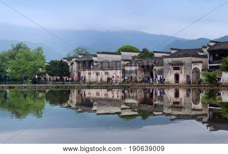 HONGCUN, CHINA - APRIL 20, 2014: Tourist walking around Moon Lake in Hongcun Village. Hongcun is ancient village in Anhui Province near the southwest of Mount Huangshan.