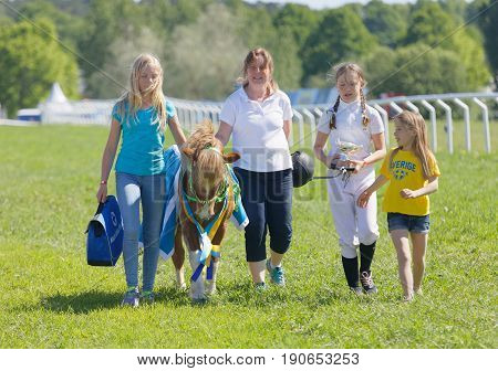 STOCKHOLM SWEDEN - JUNE 06 2017: Happy winning jockey of a pony gallop horse race and her proud family at Nationaldags Galoppen at Gardet. June 6 2017 in Stockholm Sweden