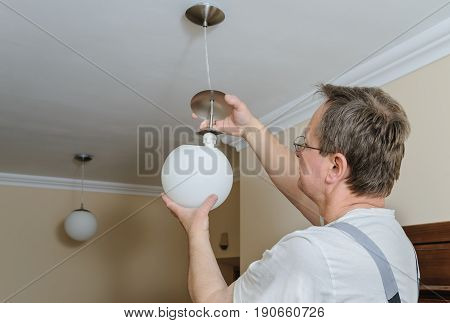 Electrician is instilling a ceiling lamp with led bulb.
