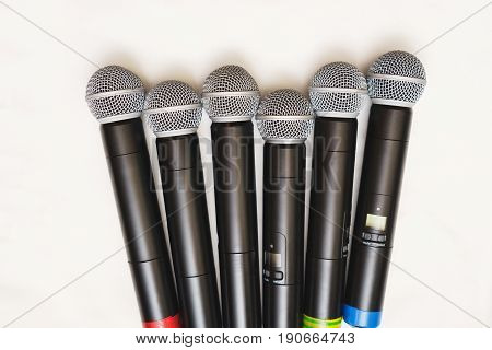 Top view of six black wireless professional microphones prepared for leading or musicians on a white background, isolate. Sound equipment for entertainment and performances by artists.