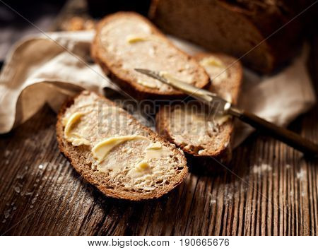 Slices of rustic sourdough bread with homemade butter on wooden table