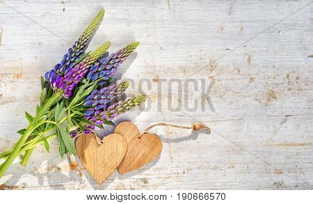 Two Wooden Hearts And Bouquet Of The Blue Lupine Flowers On A Wooden Table. Copy Space For Your Text