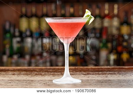 A cosmopolitan alcoholic cocktail is on the bar in a restaurant or in a club. Blurred background of alcohol.