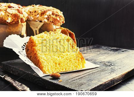 Slice of Colomba - italian easter dove cake on old rustic black wooden board. Selective focus free text space.