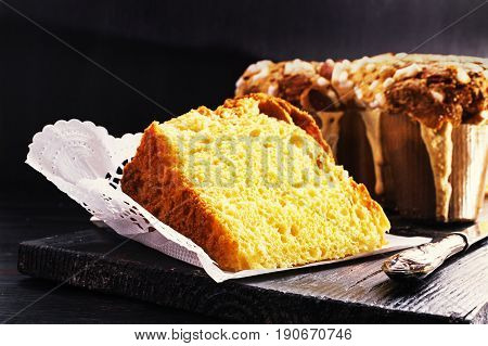 Slice of Colomba - italian easter dove cake on old rustic black wooden board. Selective focus free text space.