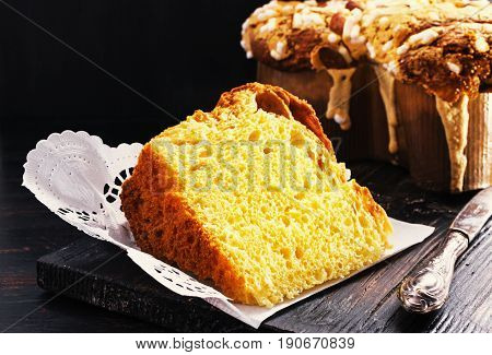 Slice of Colomba - italian easter dove cake on old rustic black wooden board. Selective focus free.