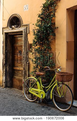 Old street in Trastevere in Rome, Italy, stylish bycice parked in front of shop entrance