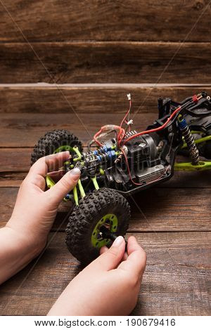 Rc radio control car crawler model repair on wooden background. Green toy suv in repairshop workplace, free space