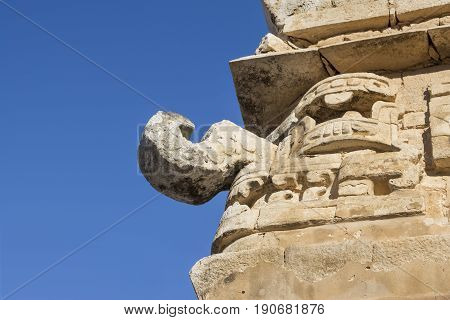 Closeup low angle stone sculpture of rain god Chaac on corner of temple building at Chichen Itza on clear sunny day in Yucatan Mexico