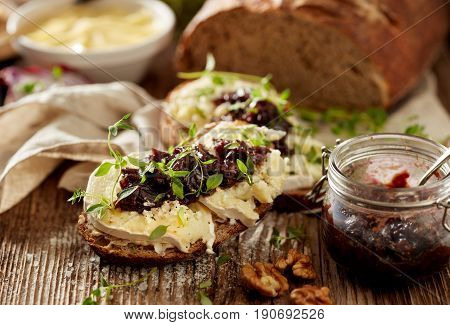 Sandwiches with goat's bread with goat cheese, caramelized red onion and fresh thyme on wooden table