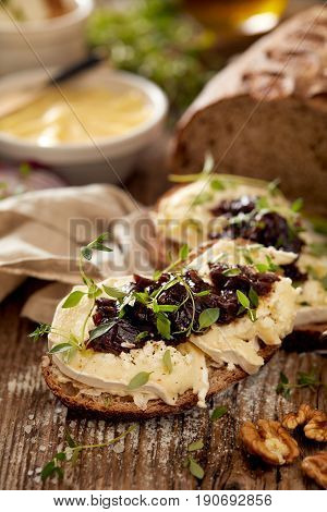 Sandwiches with goat's bread with goat cheese, caramelized red onion and fresh thyme on wooden table