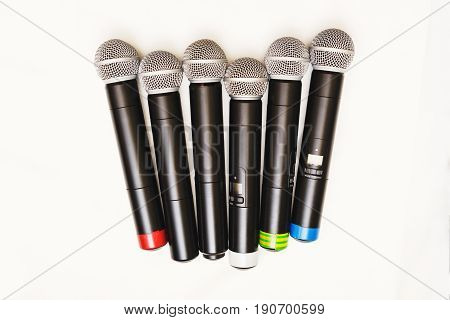 Top view of six black wireless professional microphones prepared for leading or musicians on a white background, isolate. Sound equipment for entertainment and performances by artists.