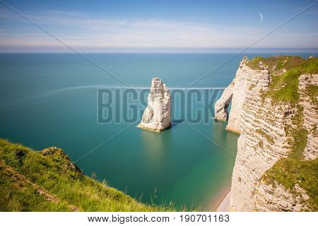 Landscape view on the famous rocky coastline near Etretat town in France during the sunny day. Long exposure image technic with soft water