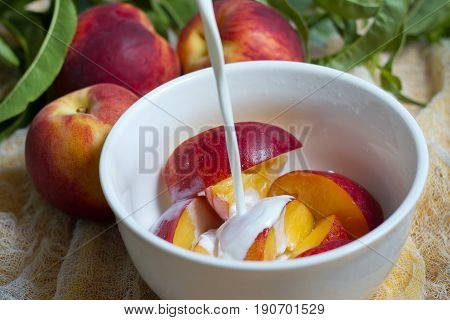 cream pouring over a bowl of fresh local peaches
