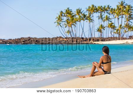 Hawaii beach travel tropical getaway bikini girl on Big island. Hawaiian tropical nature landscape with palm trees and volcanic beach in background.