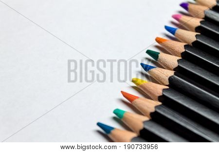 Colored pencils laid across white paper in a row