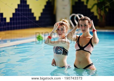 Two Cool Young Girls Wearing Bikini Pose In The Pool In The Water Park.
