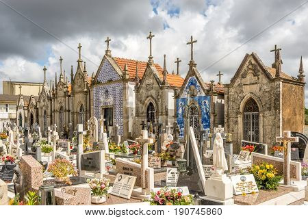 VALEGA,PORTUGAL - MAY 12,2017 - View of a typical Portuguese village cemetery near Our Lady of Amparo church in Valega. Tombs are decorated with painting and azulejo tiles.