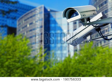 Cctv Security Camera In A City With Blury Business Building On Background