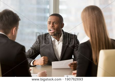 Dissatisfied african-american boss clenching fist, scolding employees for bad work, displeased team leader holding report arguing with subordinates, defrauded cheated investor demanding money back