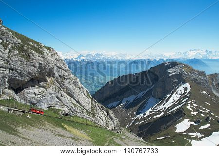 Beautiful view of snowy and green Swiss Alps and the steepest cogwheel train from the mount Pilatus in summer